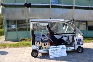Vollkabinen-Fahrrad mit Hinweisschild vor dem Haus Einstein